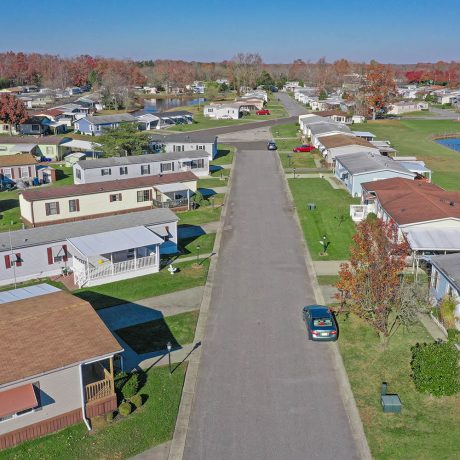 Aerial view of a street in Cranberry Run with many homes, large grassy areas and autumn trees