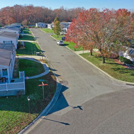 Aerial view of a street in Cranberry Run with large grassy areas and autumn trees